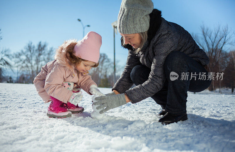 奶奶和孙女在冬天堆雪人