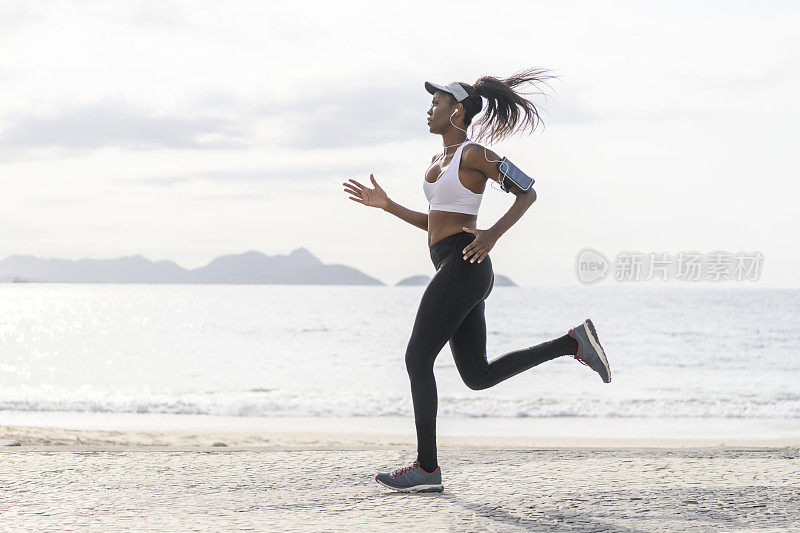 全长侧面的女人在海滩上跑步