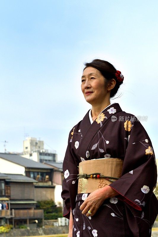 穿着和服的日本妇女在京都的秋天沿着加茂河行走