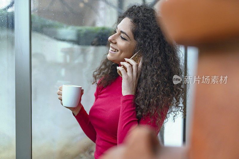 漂亮的年轻女子一边喝咖啡一边玩智能手机