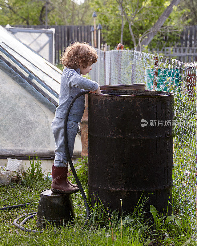 一个小女孩正往大黑桶里注水