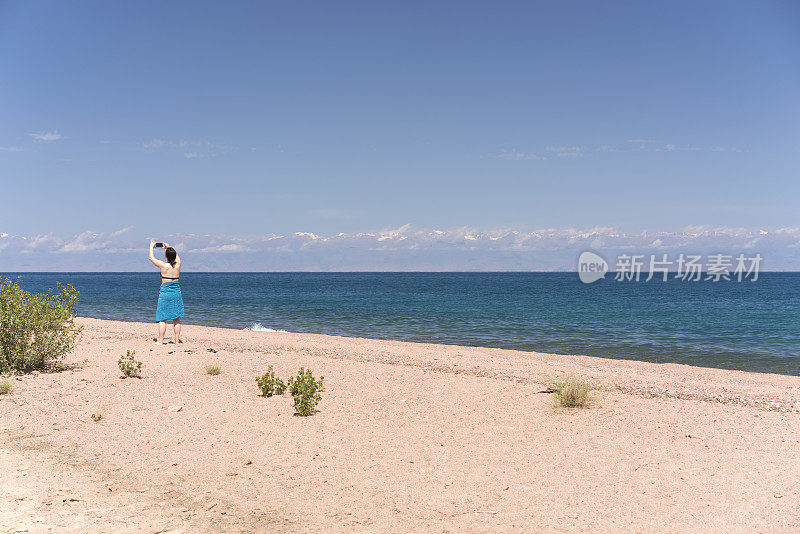 一个女人的背影，一个游客在吉尔吉斯斯坦拍摄和享受伊西库尔湖