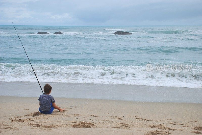 海边冲浪钓鱼的小男孩