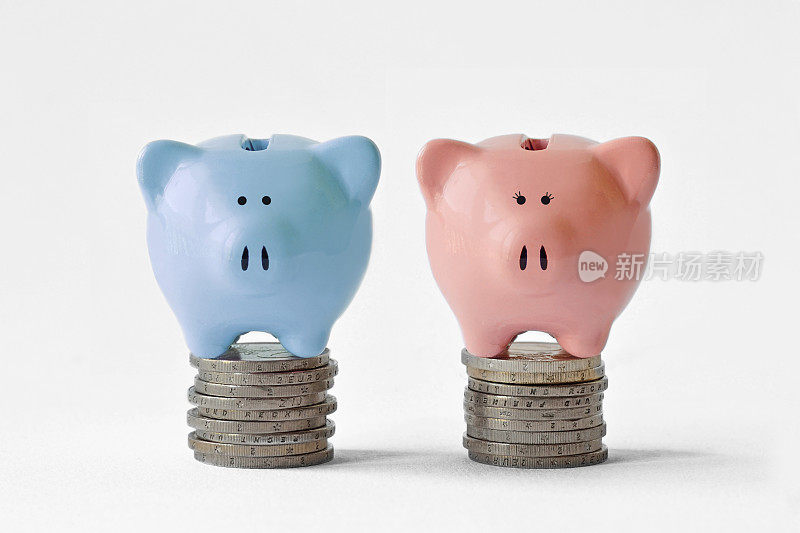一堆硬币上的蓝色和粉色储蓄罐——性别薪酬平等概念