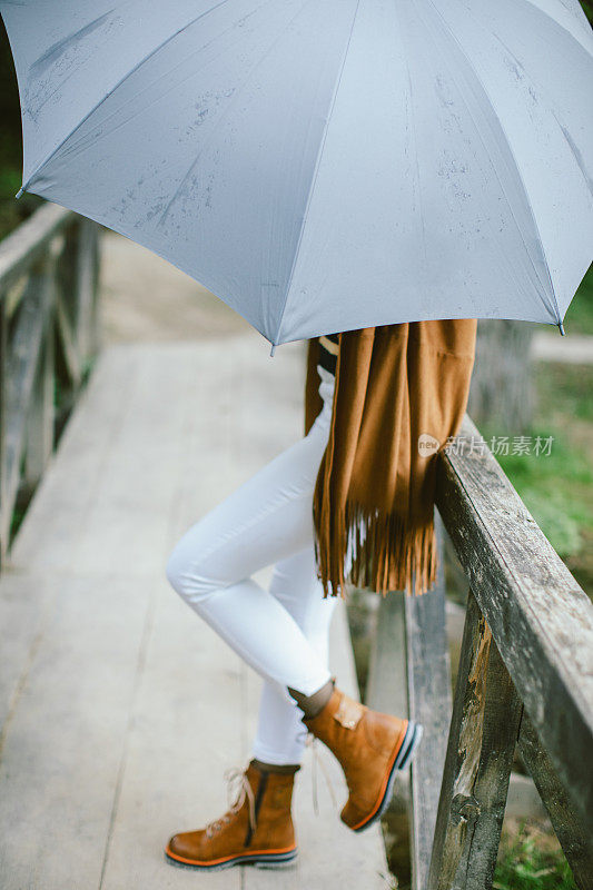 拿着伞的女人站在桥上
