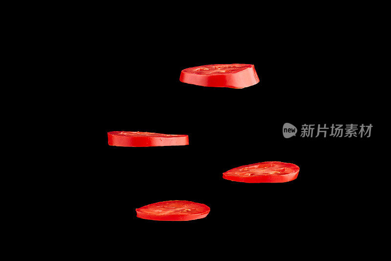 飞行番茄的创意概念。切片红番茄孤立在黑色背景。轻浮的蔬菜漂浮在空中