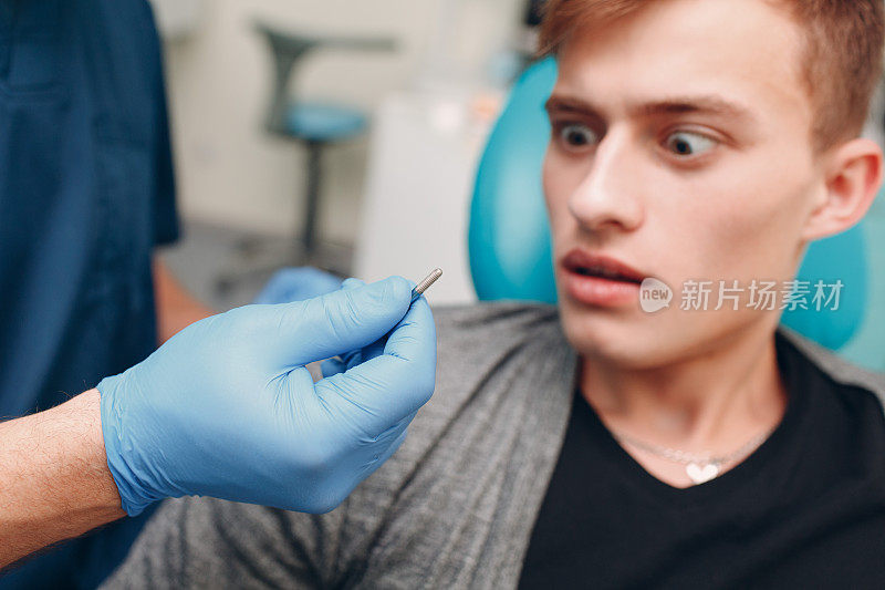 牙医。牙科医生向牙科诊所的病人展示植牙。