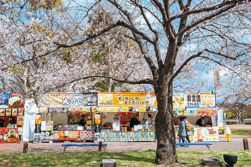 日本大阪70年世博会纪念公园的街头小吃摊上盛开的樱花