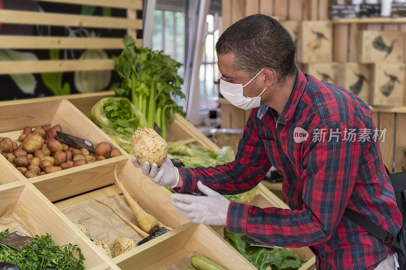 一名在杂货店里选择蔬菜的男子在疫情期间。