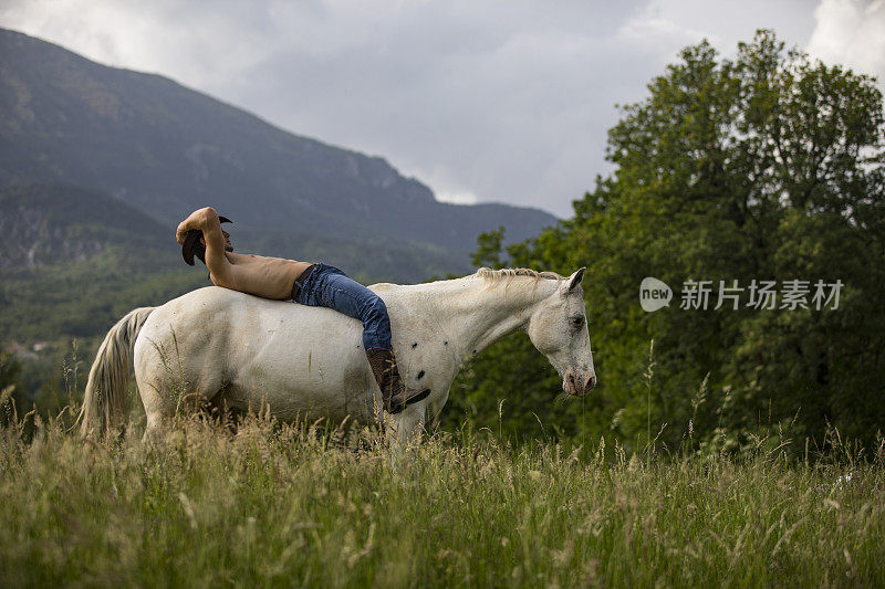 赤裸上身的年轻成年男子与牛仔帽放松在马背上