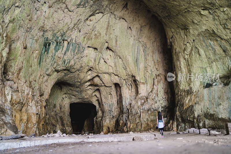 旅行者女孩在洞穴入口前，探索一个devvetashka洞穴附近的lovech
