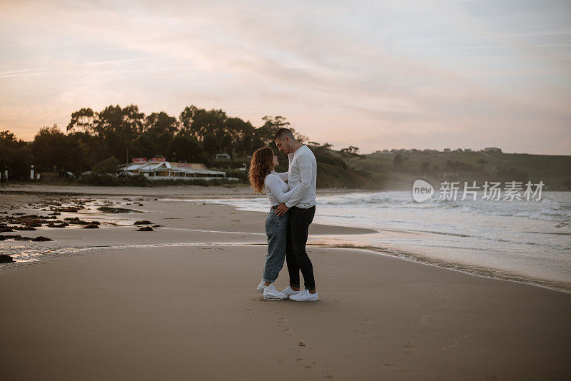 日落时分，一对年轻夫妇在海滩上