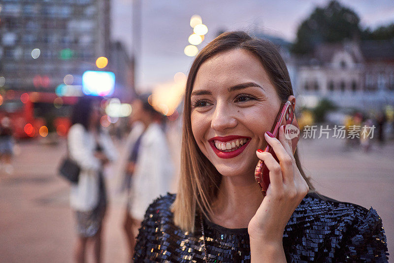 一个欢快的年轻女子在城市的户外用手机打电话