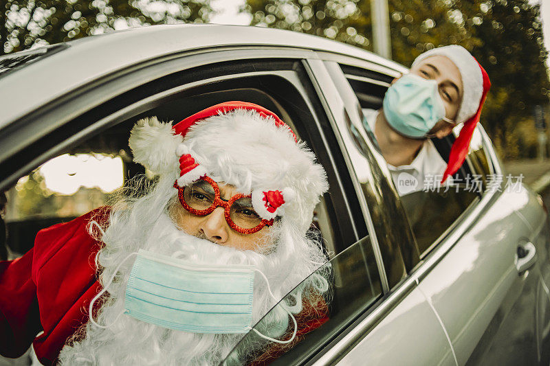 2019冠状病毒病(COVID-19)大流行时戴上防护口罩的新年晚会——准备最疯狂的新年之夜——快乐的年轻人在车里和圣诞老人开疯狂派对——新年晚会可以开始了