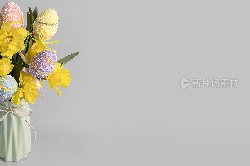水仙花和复活节彩蛋在一个花瓶在灰色的背景