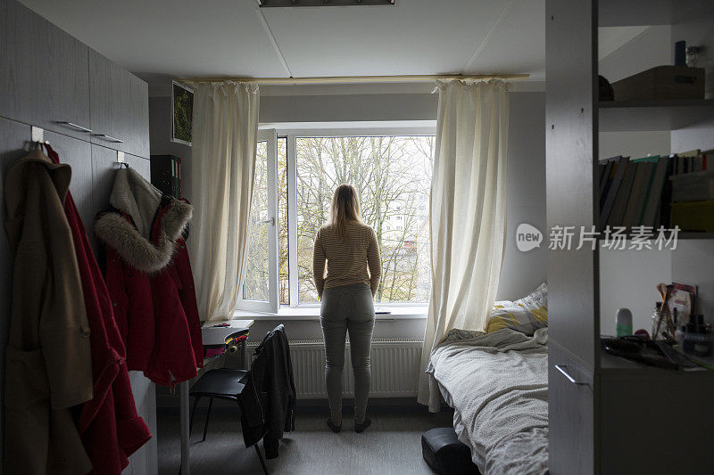 一个大学生从她的宿舍公寓望向窗外