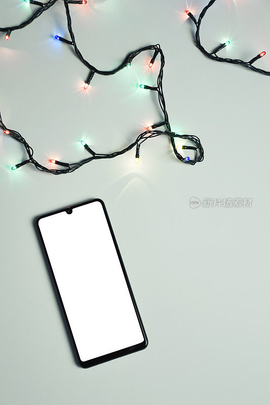 圣诞灯光和空白屏幕(剪辑路径)智能手机上的白色背景