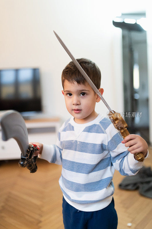 可爱的幼童玩和持有玩具剑和佩剑