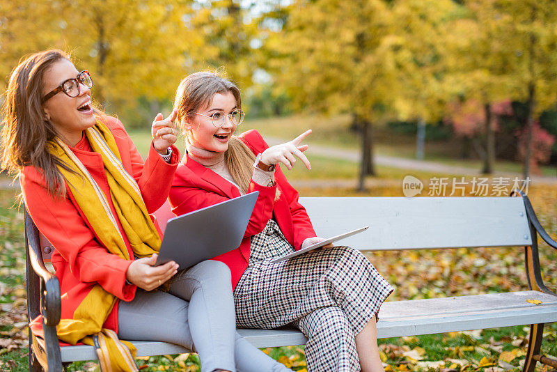 两个女商人在公园里指指点点笑个不停