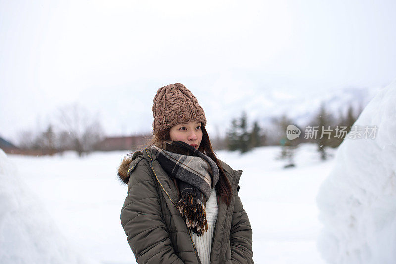 美丽的年轻女子走在雪堆之间的小路上