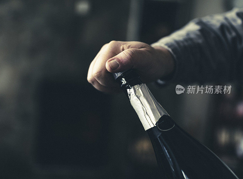 庆典的到来吧!一个人把手放在一个冰冷的起泡酒瓶的软木塞上。