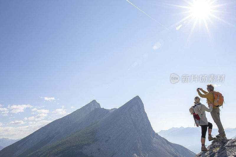 徒步夫妇攀登岩石脊顶，高于山脉