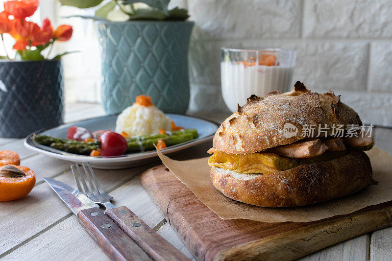 健康早餐:夏巴塔三明治，炸芦笋，土豆泥和酸奶在餐桌上