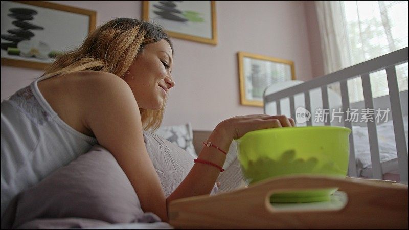 一个女人在卧室的床上一边吃樱桃一边看书。