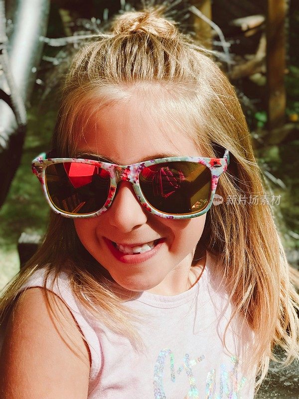 可爱的微笑女孩戴着太阳镜在户外冒险。￼