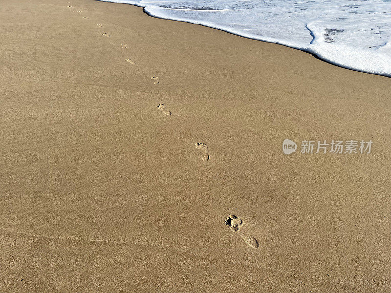 英国，多塞特，普尔湾，南海岸沙滩上的脚印消失在海里