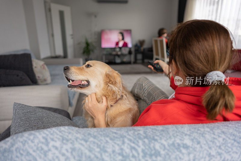 成熟的女人在家和她的狗看电影。