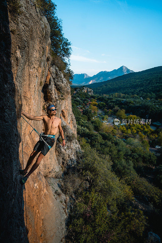 登山者在郁郁葱葱的山谷上陡峭的岩壁上停留