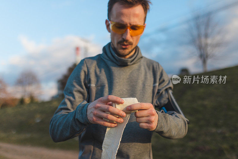 一个年轻男性跑步者滚动纱布绷带的特写镜头