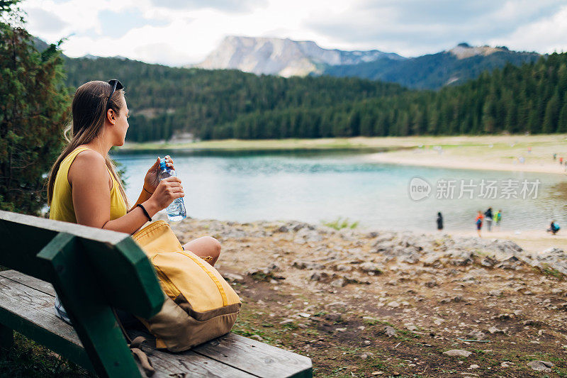她坐在离湖不远的木凳上，打开一瓶水解渴。