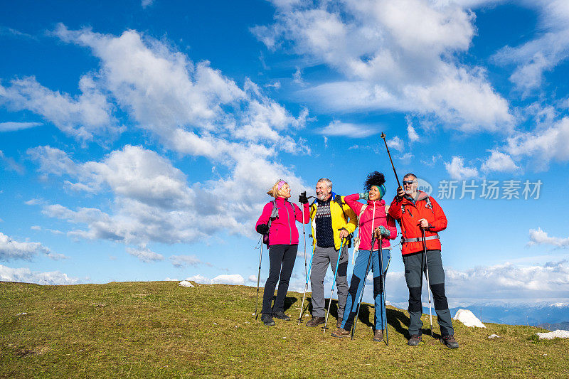 四名不同年龄的远足者站成一排，在大自然中享受阳光灿烂的日子