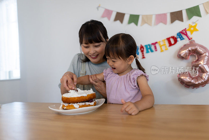 母亲和女儿在家里的生日蛋糕上抹奶油