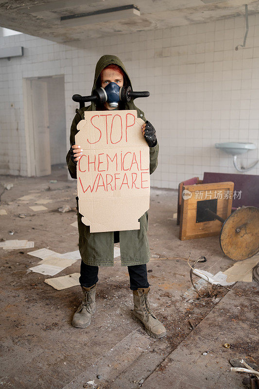 一名女军人戴着防毒面具，横幅上写着“停止化学战、世界末日、核武器、核电站的原子爆炸、保护化学武器和核武器”。