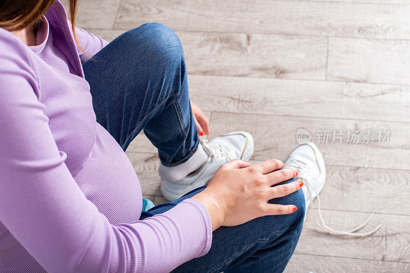 一个怀孕的女孩穿着大肚子的鞋子。怀孕期间弯腰不舒服，不方便，有问题。文本复制空间