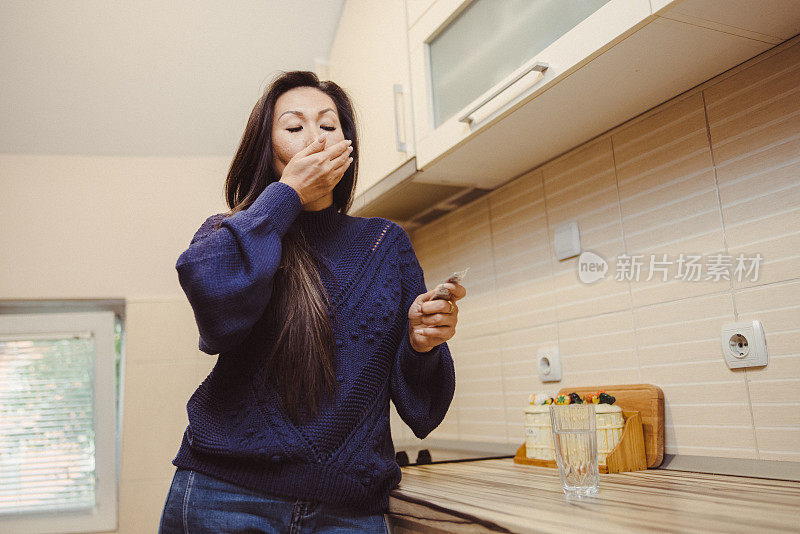 美丽的亚洲妇女在家里吃药