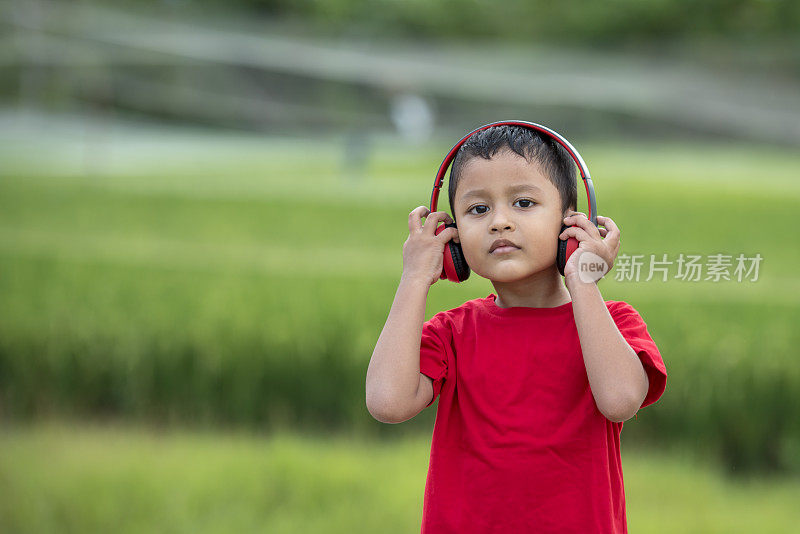 蹒跚学步的男孩用耳机听音乐