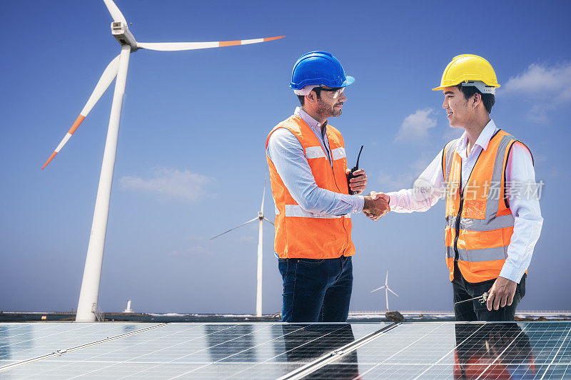 太阳能和风力发电厂可再生能源。工程师和青年技术人员在风力太阳能电站附近握手。