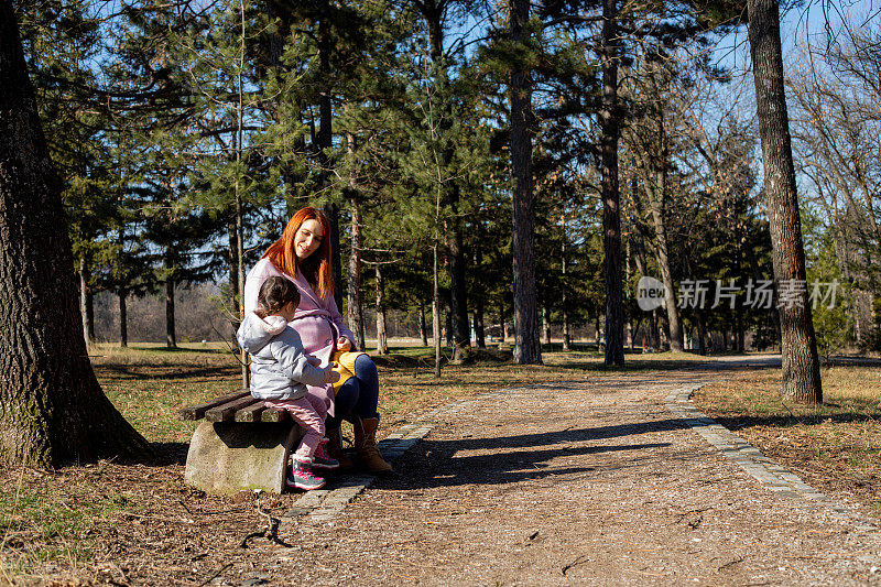 孕妇和她的孩子正坐在森林里的长凳上