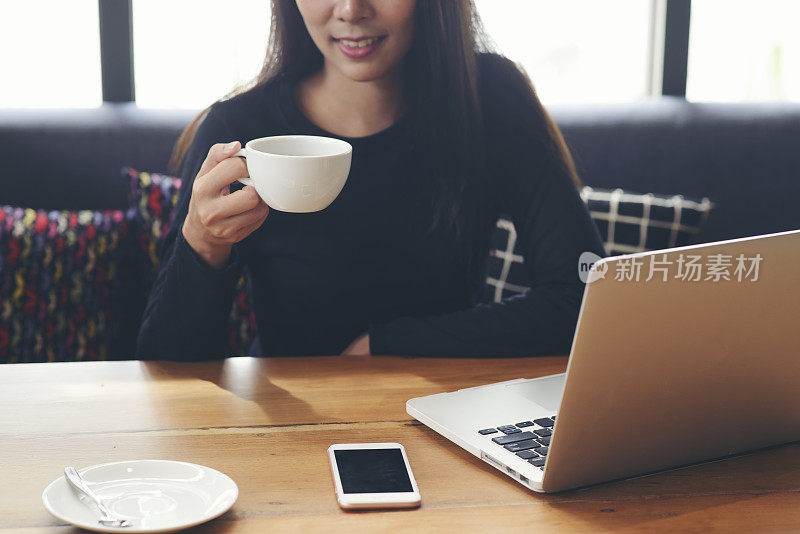 在家远程办公概念。女商人通过笔记本电脑上网工作，喝咖啡。亚洲年轻企业家观看网络研讨会，并在会议期间与团队进行视频会议