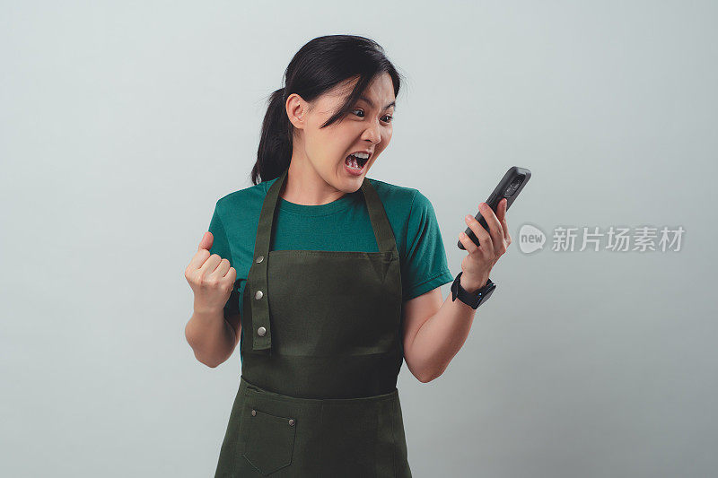 穿着围裙用智能手机说话的亚洲女子与顾客发生冲突。