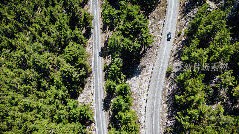 在森林山区的道路上行驶的车辆用无人机拍摄沥青弯道