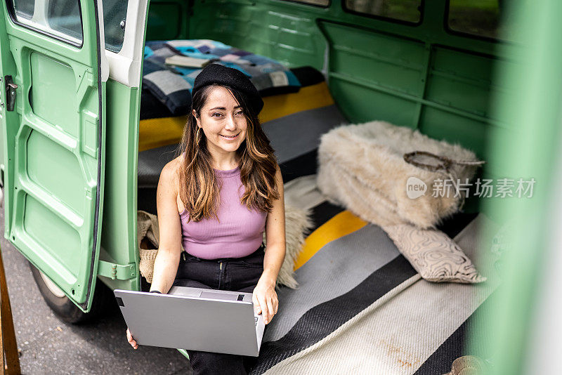 一个中年妇女在一辆复古的小货车里使用笔记本电脑的肖像