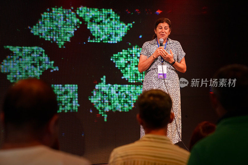 一位女士正在舞台上做关于生态学的演讲。