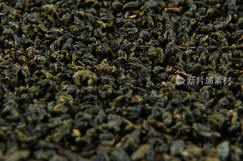 黑色干茶壁纸。在转盘上旋转混合红茶和绿茶。特写，微距。前视图。纹理。完整的框架。副本的空间。干茶在纺纱。深色抽象食品饮料背景