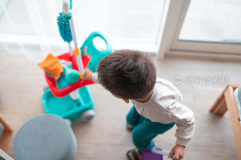 两岁半的小男孩开心地玩着他的清洁套装玩具和家务活动