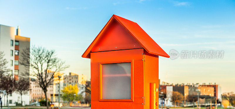 一个小型的红色木屋仿制品，衬在住宅区的房屋建筑上。概念:房地产，买卖和出租房屋。